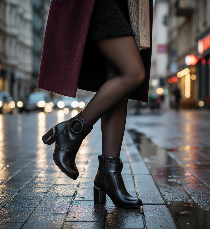 Person wearing black ankle boots on a wet city street