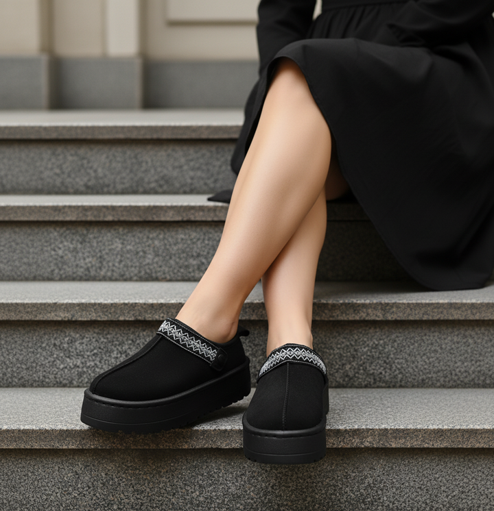 Person wearing black loafers with decorative straps sitting on steps.