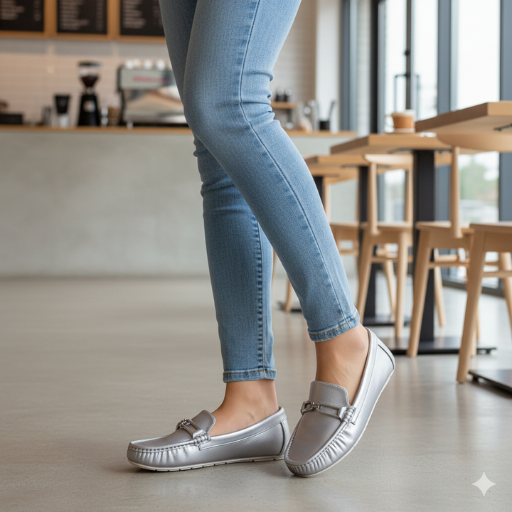 Person wearing silver loafers and light blue jeans in a casual setting